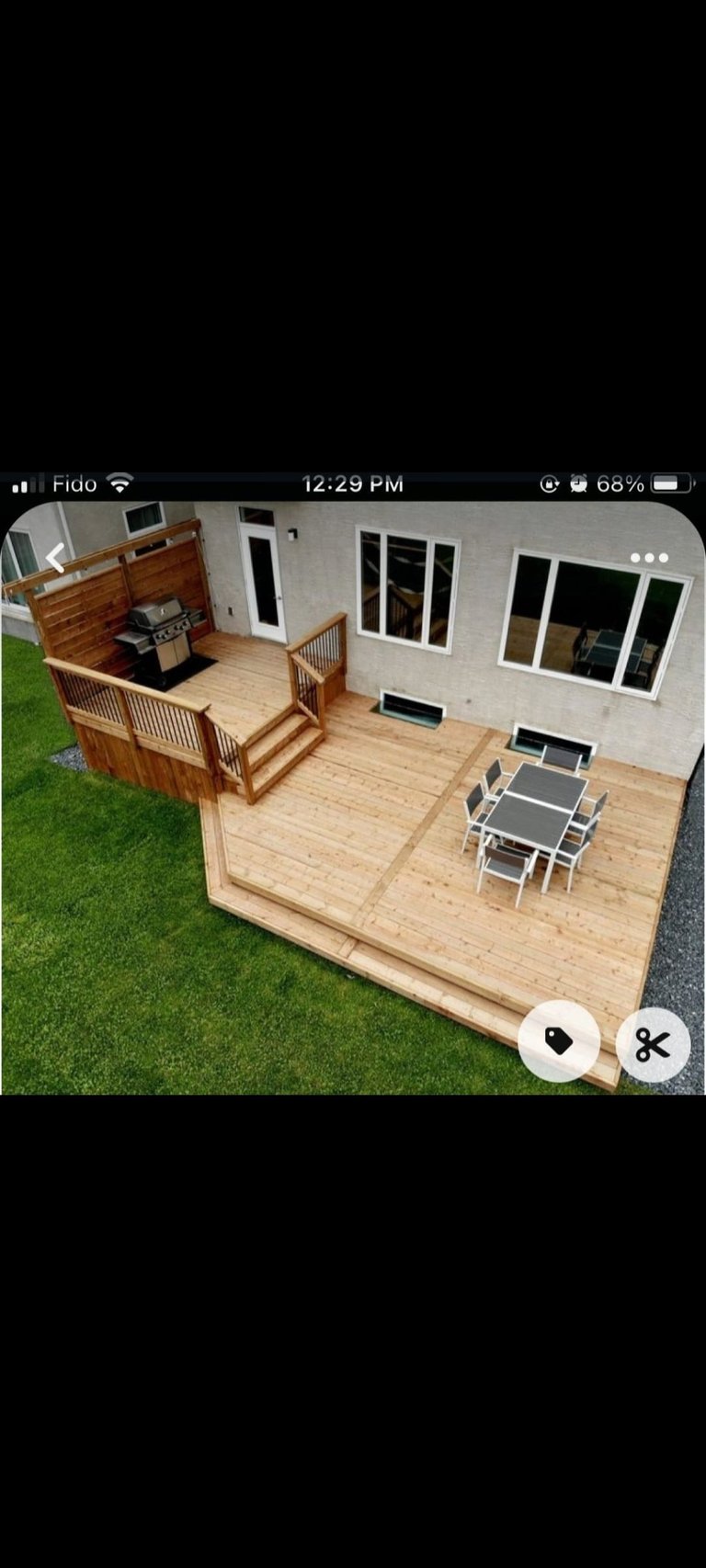 Overhead view of a wooden deck with railing, grill, and dining table in a backyard adjacent to a house with lawn