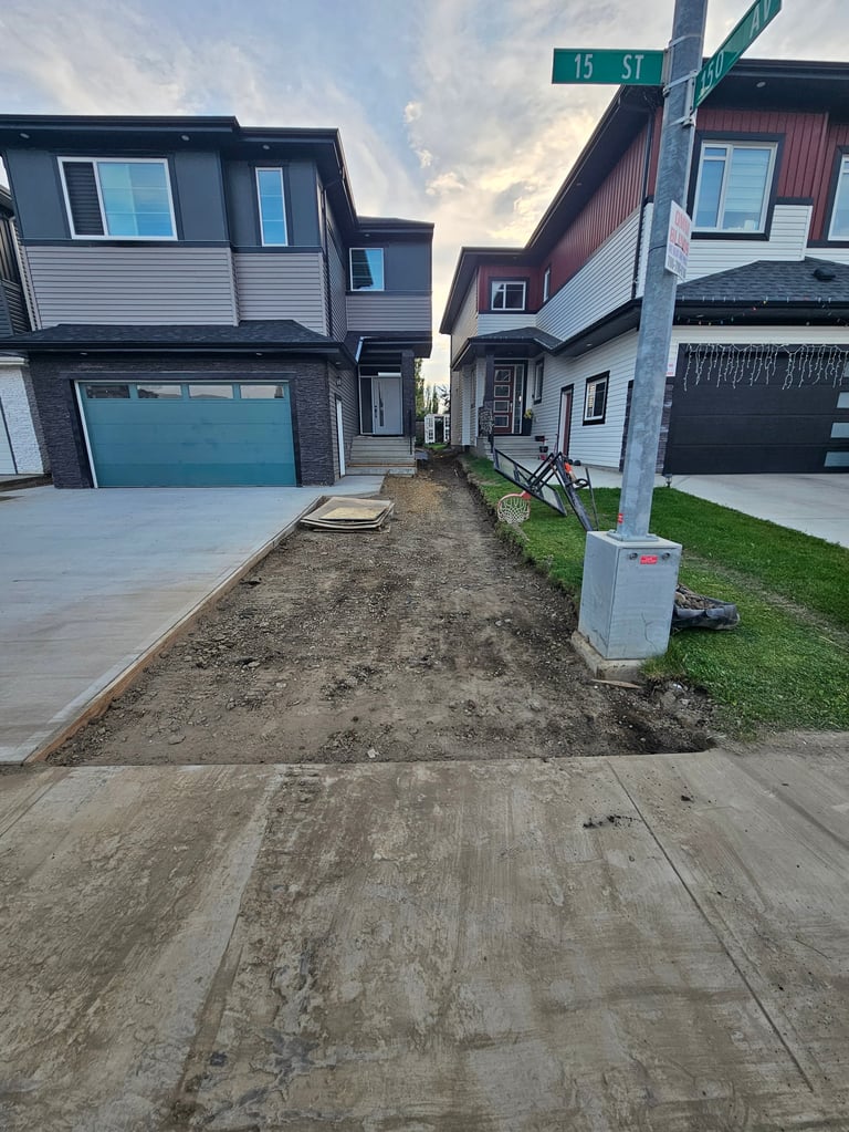 Suburban street with modern two-story homes, turquoise garage doors, and dirt driveway under construction, 15 ST street sign visible