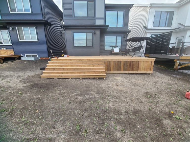 Wooden deck under construction in a residential backyard with modern houses in the background